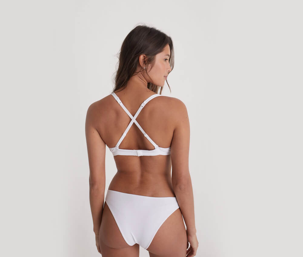 Foto de uma mulher de costas. Ela usa um dos tipos de sutiã Insider, o Flex na cor branca, de alças cruzadas nas costas.