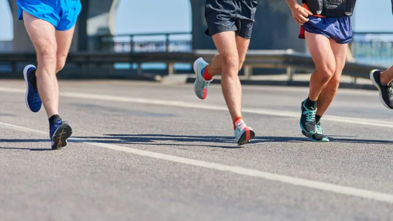 Corredores em prova de rua usando shorts esportivos, ilustrando assadura na coxa durante corrida de longa distância.