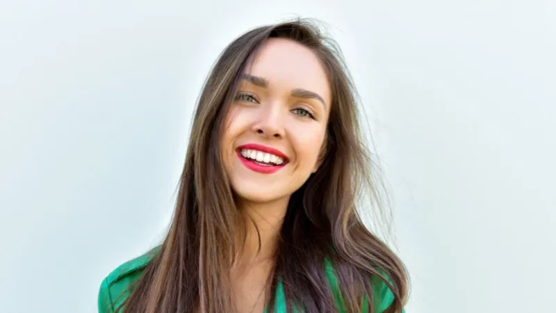 Modelo com vestido verde e maquiagem com batom vermelho vibrante destacando o visual elegante.