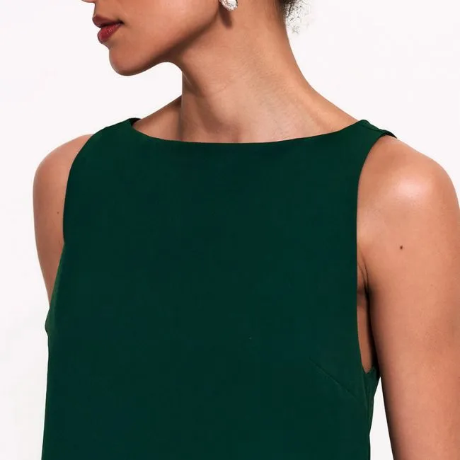 Close de vestido verde sofisticado com decote moderno e pele iluminada com maquiagem leve.