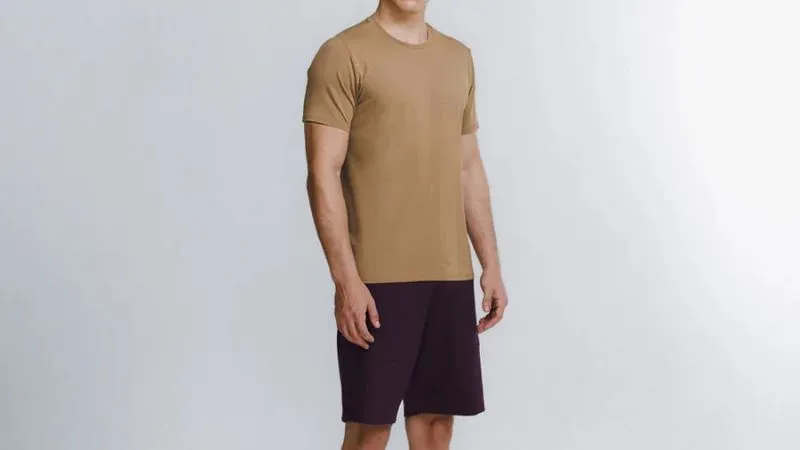 Conjunto casual masculino com camiseta bege e bermuda escura, estilo moderno e confortável.